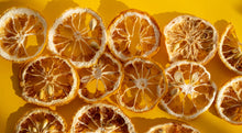 Load image into Gallery viewer, Slices of Dehydrated Yuzu - the imperfect bunch on a yellow background.
