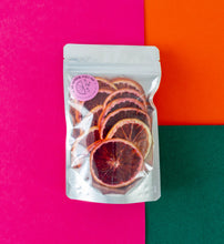 Load image into Gallery viewer, A large pack of dehydrated blood orange on a pink-orange-green background. 
