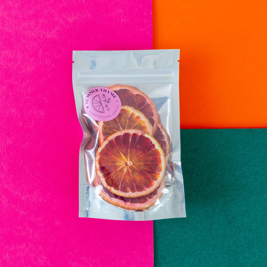 A small pack of dehydrated blood orange on a pink-orange-green background.
