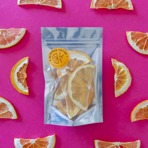 Dehydrated grapefruit half wheels in a small package on a pink background.