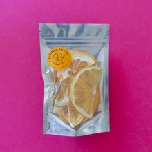 Load image into Gallery viewer, Dehydrated grapefruit half wheels in a large package on a pink background.
