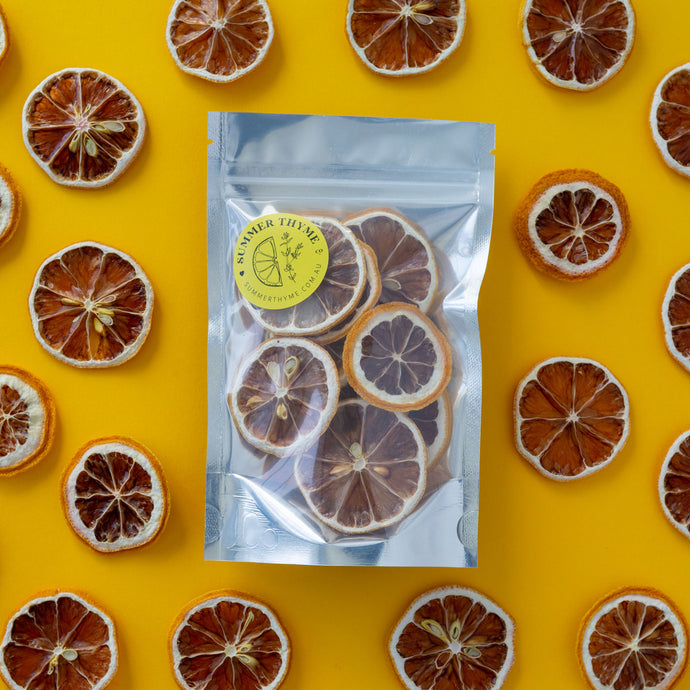 Dehydrated lemon slices arranged around a small pack of dehydrated lemons on a yellow background.