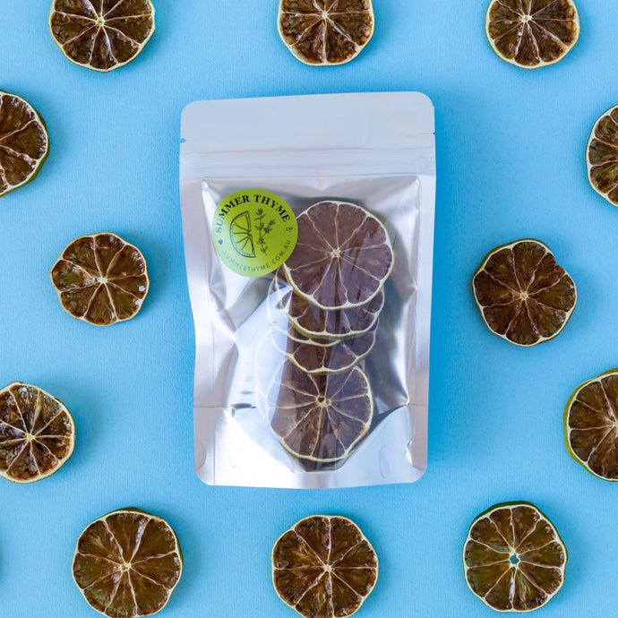 Slices of dehydrated limes arranged around a small pack of dehydrated limes on a light blue background.