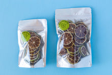 Load image into Gallery viewer, Small and large Summer Thyme Co. packs of dehydrated lime citrus garnish next to each other on a light blue background.
